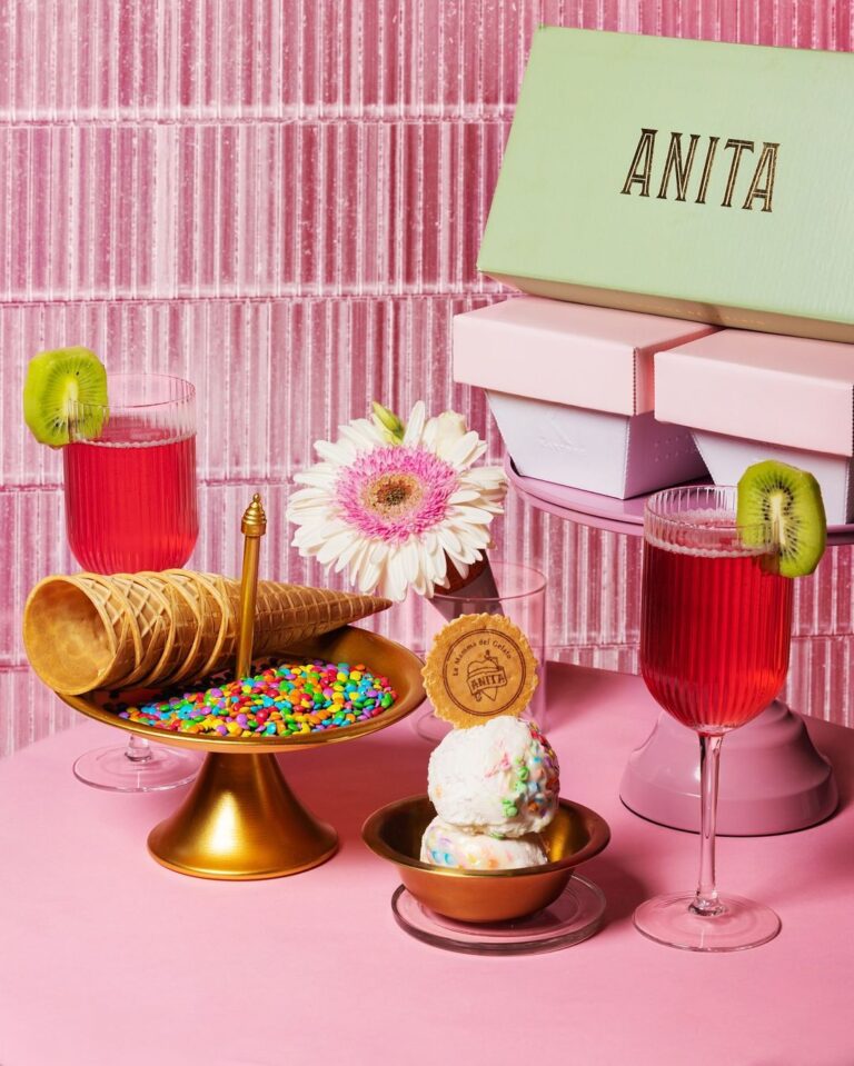 there is a pink table with a cake and a glass of wine