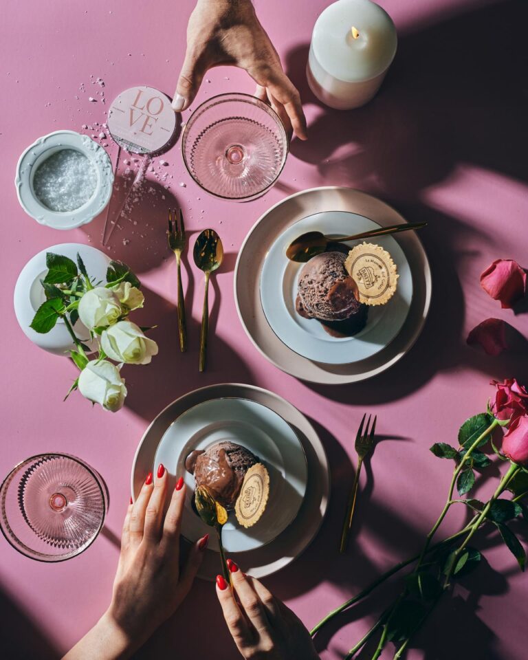 someone is eating a dessert on a plate with a candle and flowers