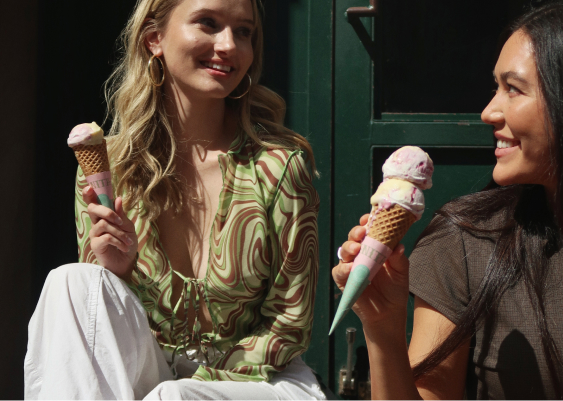 Two women sitting outside enjoying ice cream cones.