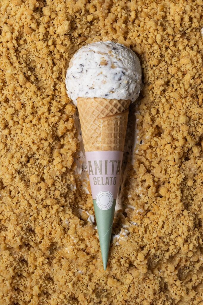 there is a scoop of ice cream in a cone on a bed of sand