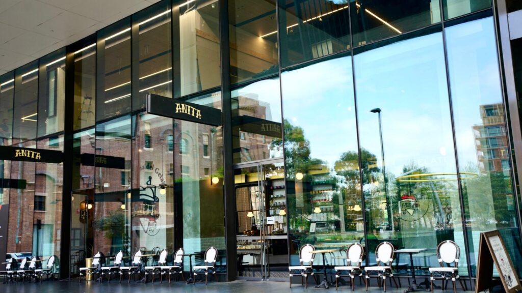 there are tables and chairs in front of a large glass building