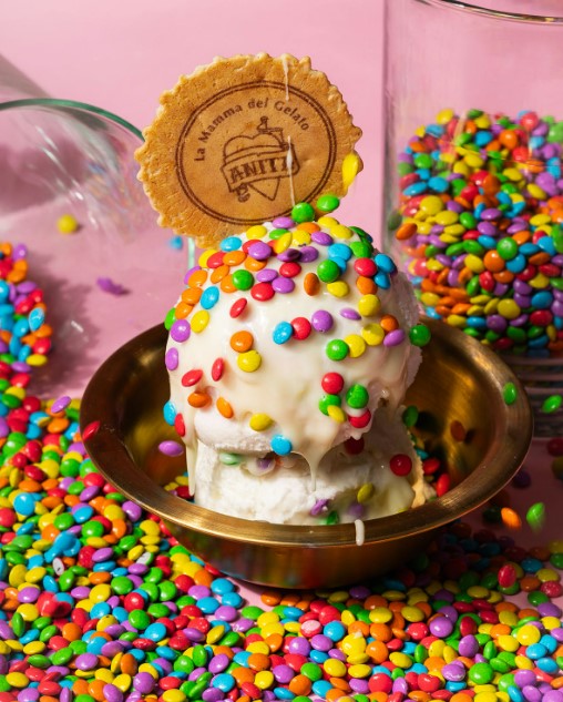 there is a small bowl of sprinkles and a cookie on top