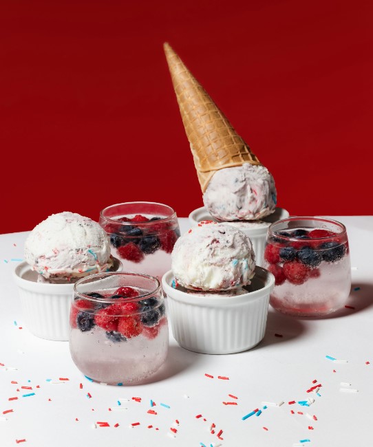 a close up of a table with cups of ice cream and berries
