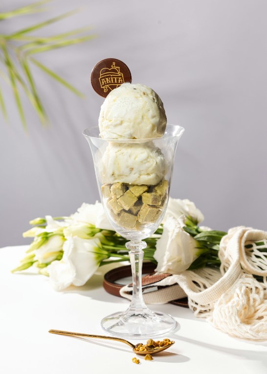 there is a glass of ice cream with a spoon and flowers