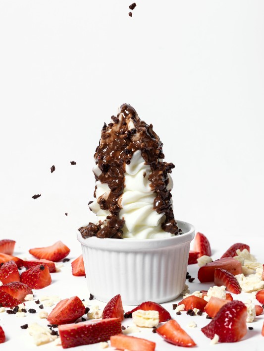 there is a cup of ice cream with chocolate and strawberries