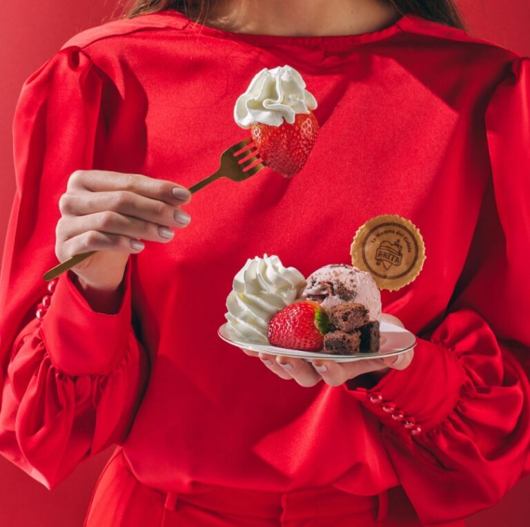 woman in red dress holding a plate of desserts and a fork
