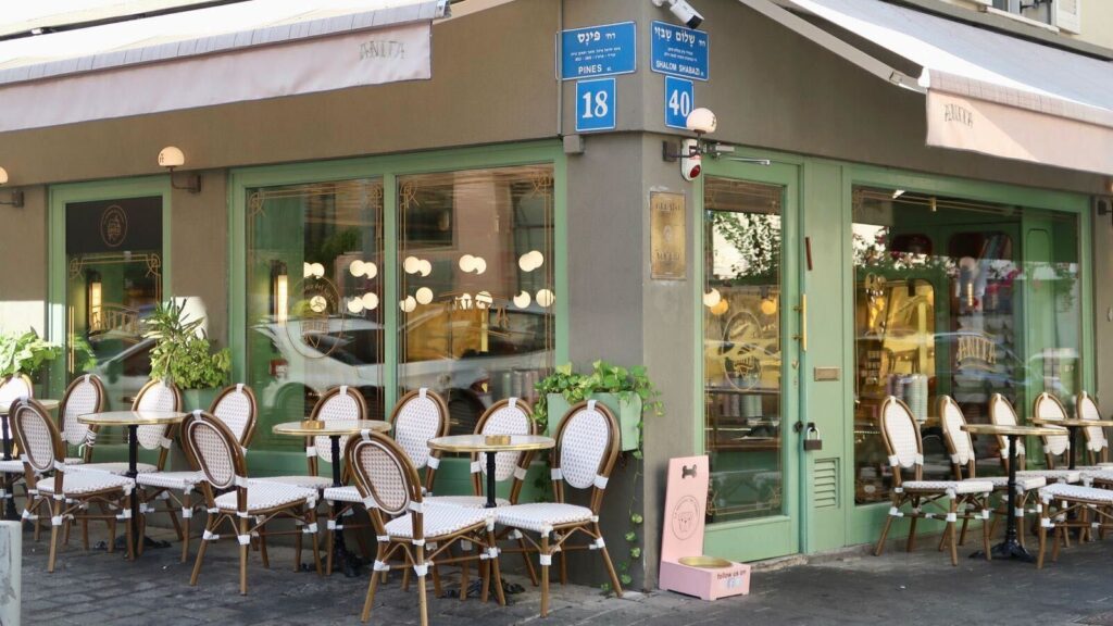 tables and chairs outside a restaurant with a sign on the sidewalk