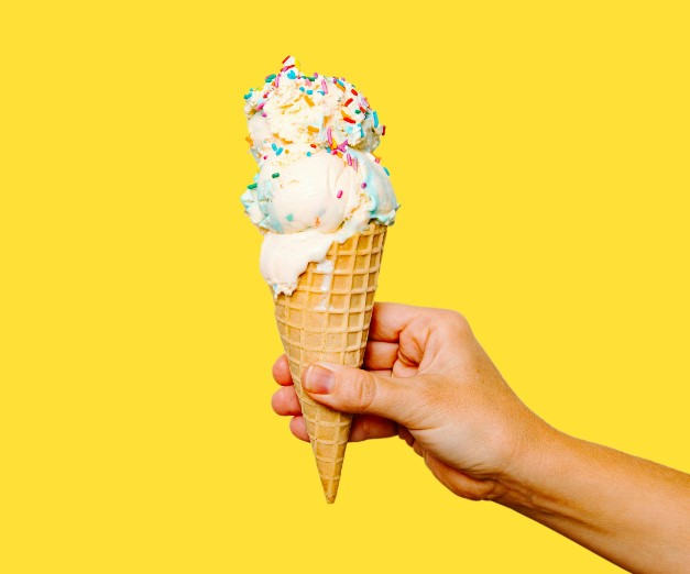 someone holding a cone with a scoop of ice cream in it
