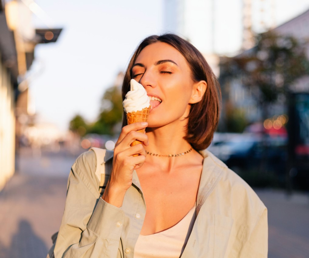 woman eating ice cream cone on city street in urban setting