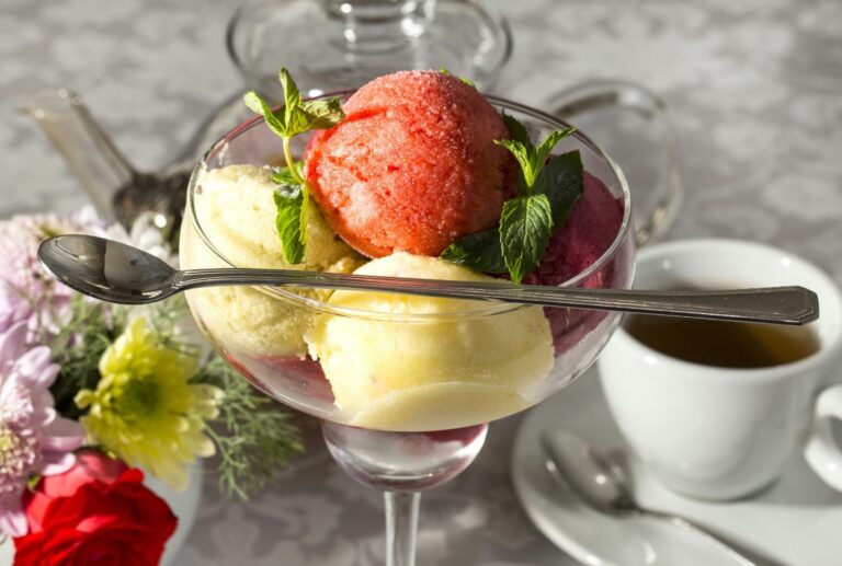there is a glass bowl of ice cream with a spoon and a cup of coffee
