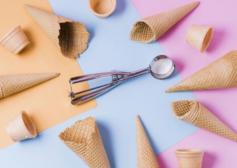 there are many cones of ice cream and spoons on a colorful surface