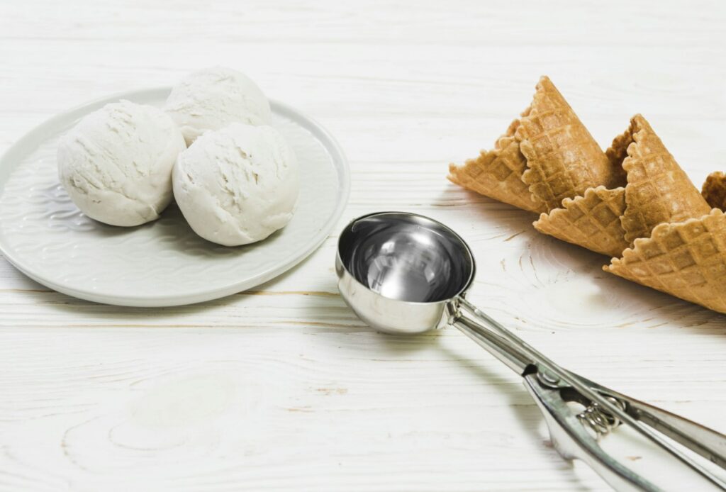there are three scoops of ice cream on a plate next to a scoop of ice cream