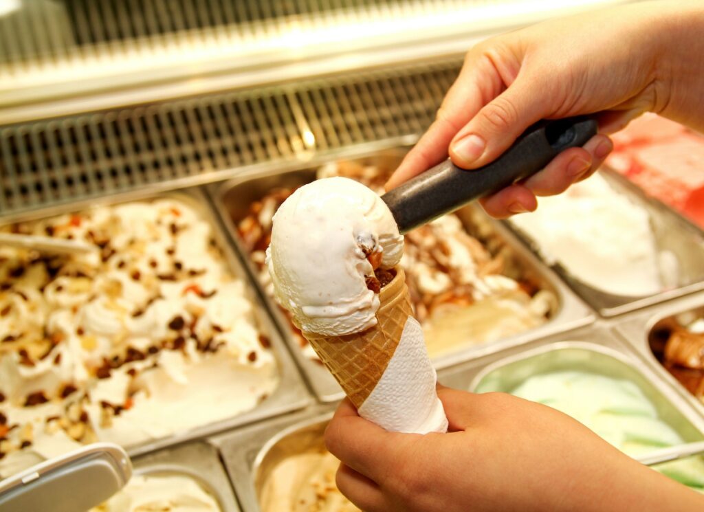 someone is holding a cone of ice cream in front of a display case