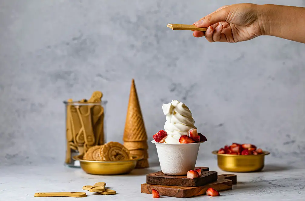 someone is holding a spoon with a scoop of ice cream and strawberries